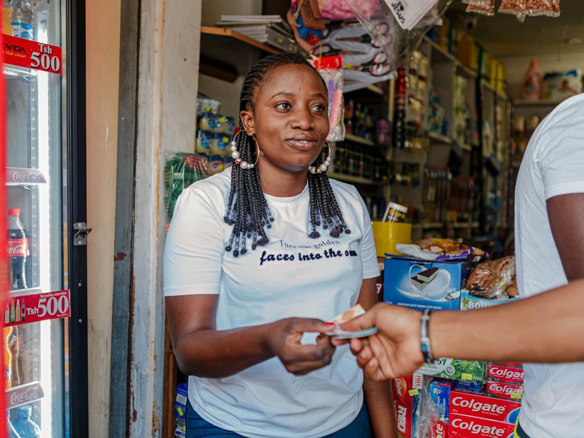 A shopkeeper handing an item to a customer over the counter